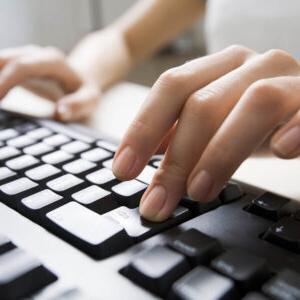 一位女士在黑色的电脑键盘上打字